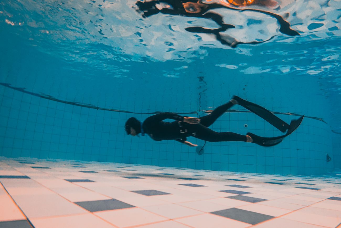 A swimmer underwater in a clear blue pool